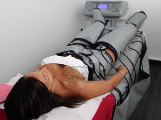 donna sdraiata su lettino con vita fianchi gambe caviglie piedi con guaina di pressoterapia